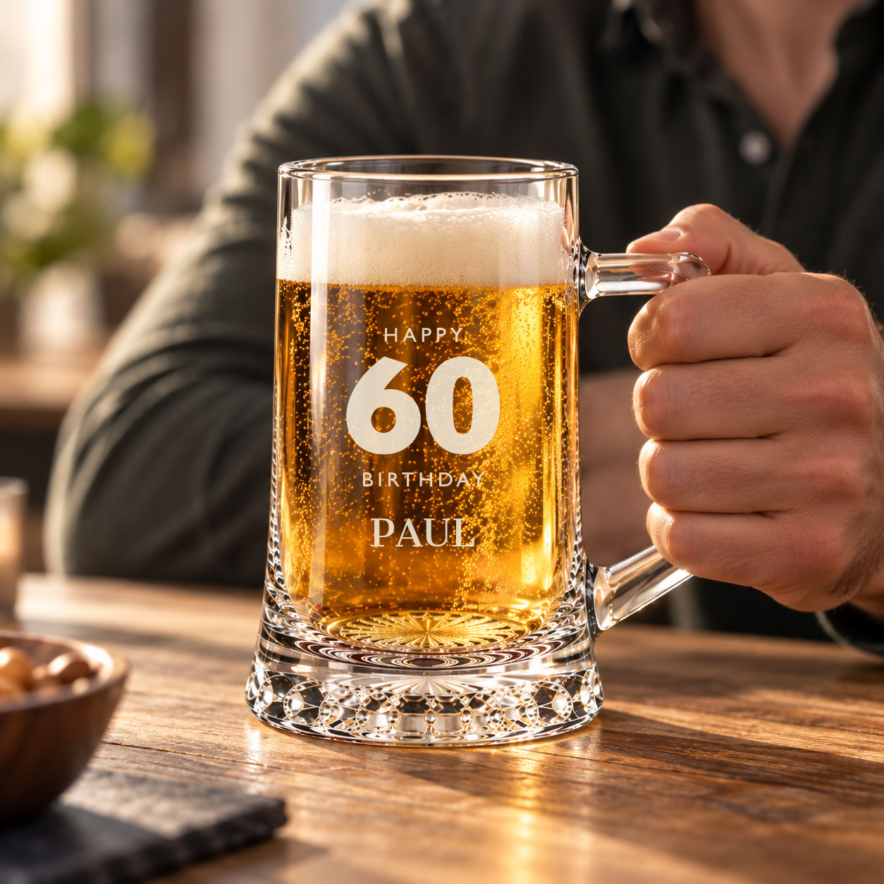 Traditional 1 pint glass tankard filled with beer and held by hand